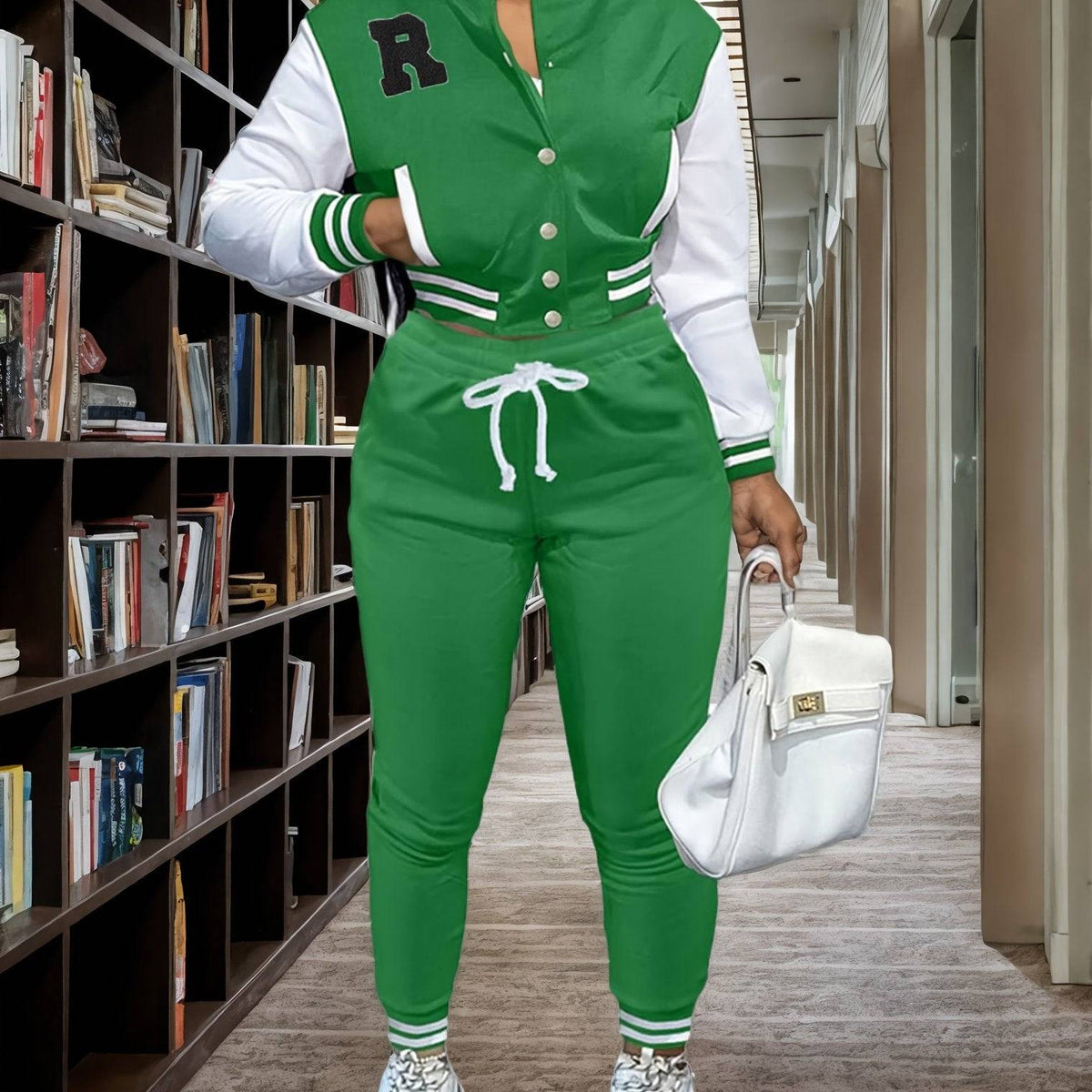 Green women’s 2-piece sportswear set with varsity jacket and jogger pants, styled for a sporty and fashionable look in a library setting.