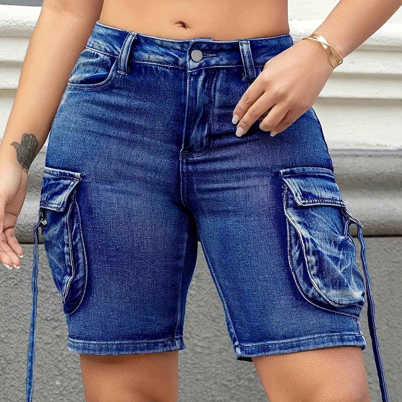 Close-up of plus size women's denim shorts with low-rise cut, stretch fit, and oversized side accordion pockets.