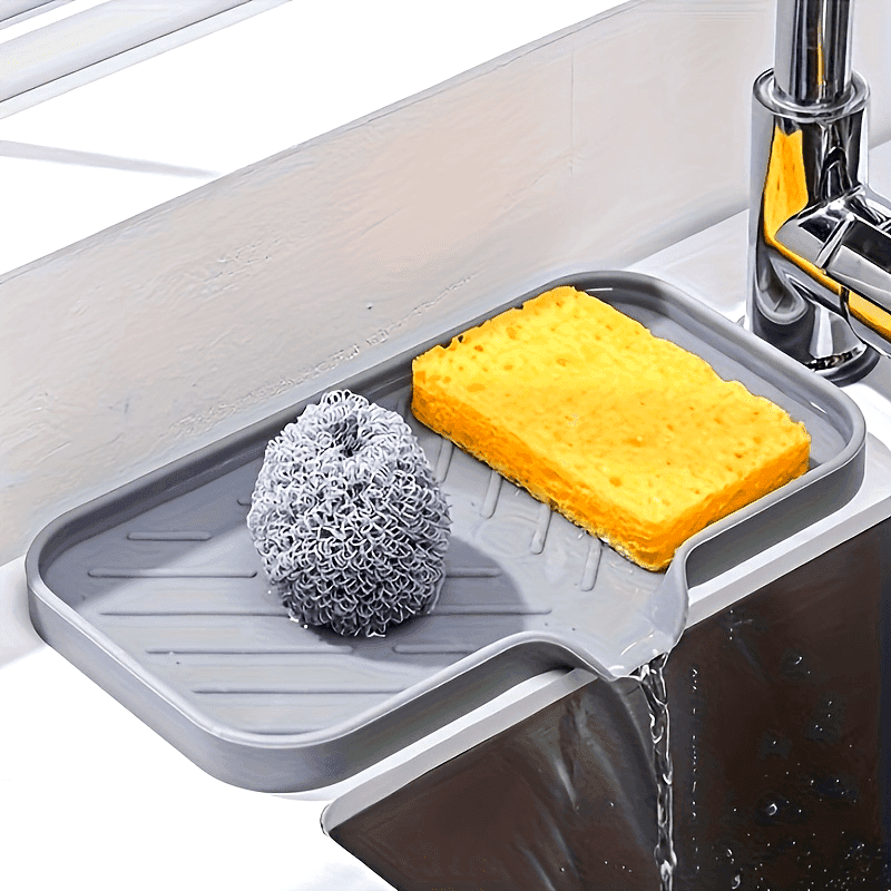 Silicone sink tray with sponge and scrubber draining water into sink, designed for kitchen and bathroom countertop organization.