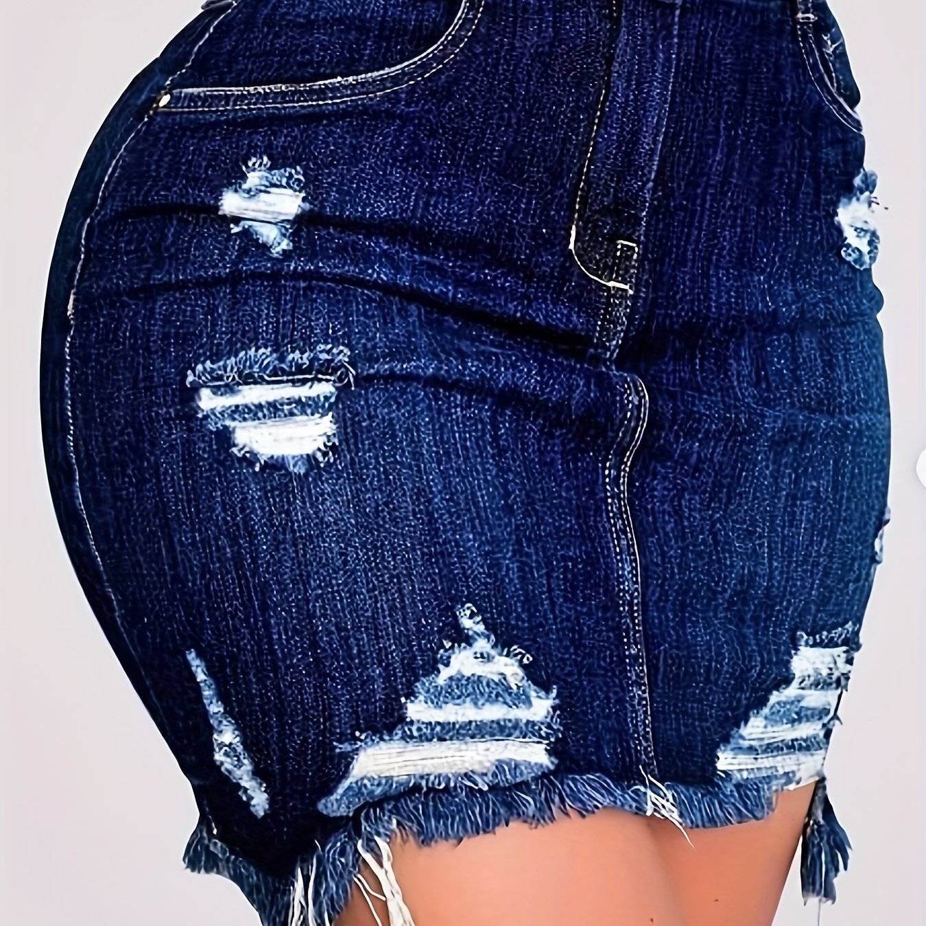 Close-up of distressed high-waisted denim skirt in blue wash with frayed hem, designed for versatile 3-season casual styling.