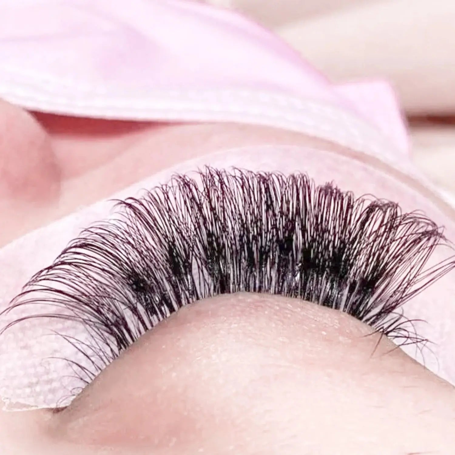 Close-up of Individual Eyelash Extensions 8–20mm Faux Mink Matte Lashes applied on eye pad for professional salon use. Features soft, natural jet black finish.