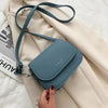 Blue vintage PU leather crossbody bag on beige fabric