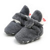 Dark gray fuzzy newborn shoes with white trim