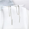 Close-up of long tassel earrings with textured metal chain