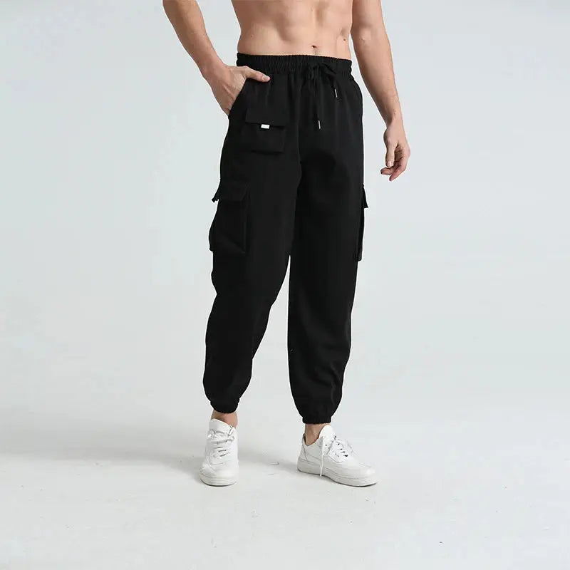 Front view of black men’s lightweight cargo hiking pants with drawstring waist and multiple flap pockets for storage and convenience.