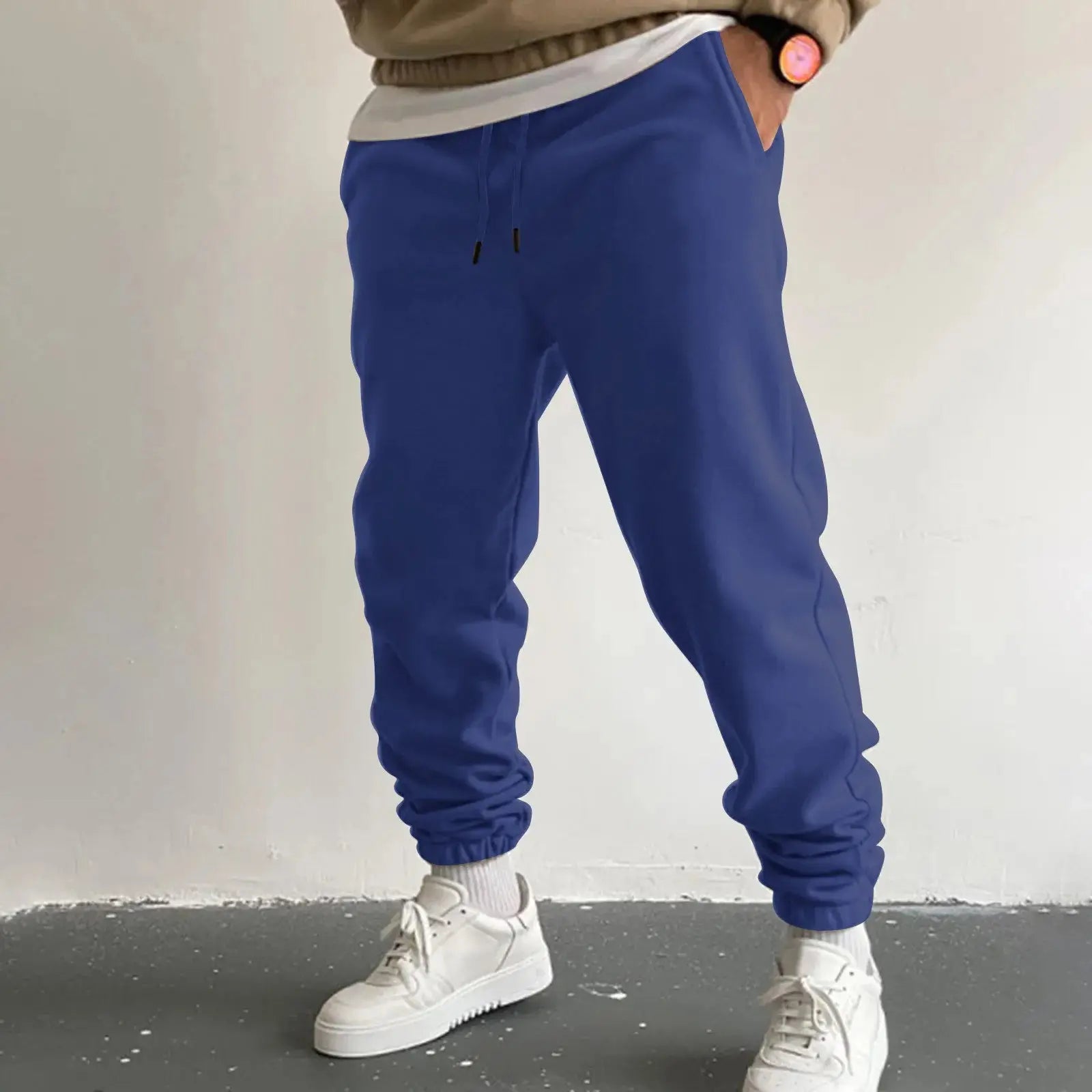 Men’s blue jogger sweatpants with high waist drawstring and side pockets, loose fit trousers for casual or athletic wear, paired with white sneakers.