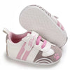 White and pink baby sneakers with paw print