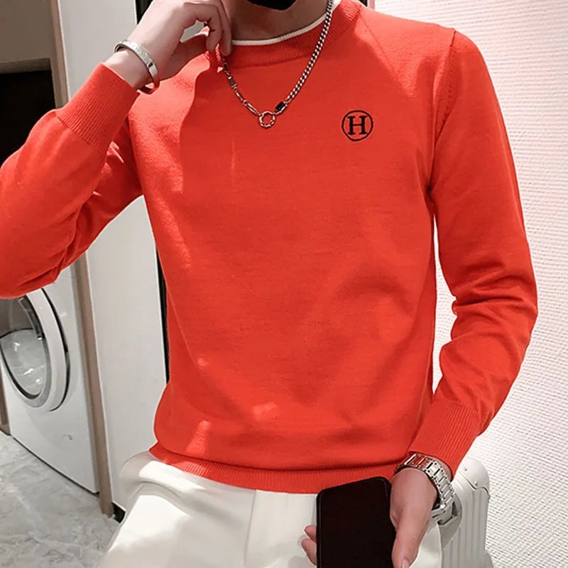 Bright orange luxury men's golf sweater with logo detail.