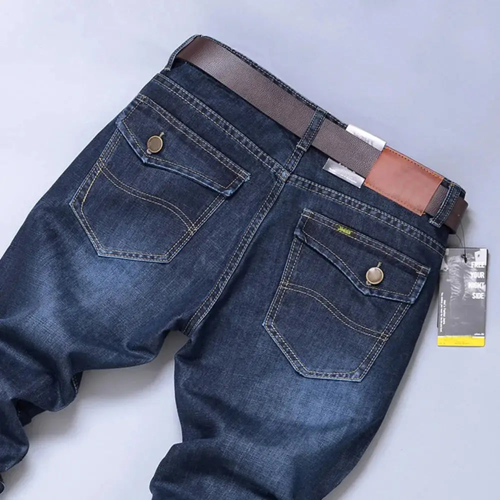 Rear pocket and waistband detail of men’s stretch denim jeans with buttoned pockets and leather patch accent.