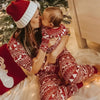 Mother and baby in matching Christmas pajamas by a tree