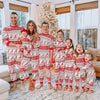 Family in matching Christmas pajamas by a decorated tree