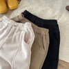 Close-up of kids' warm winter pants in beige, brown, and black.