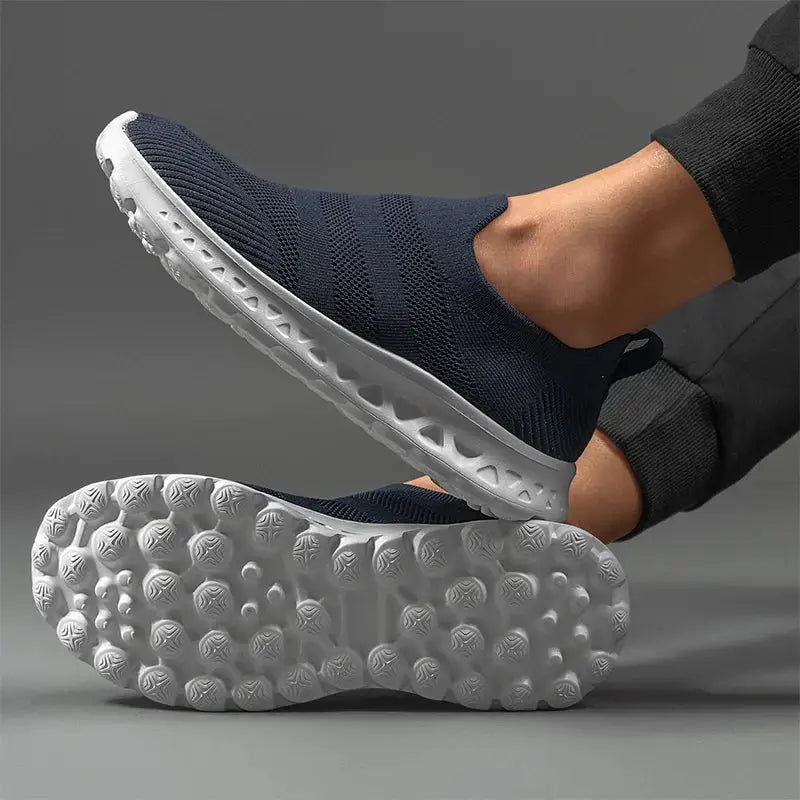 Close-up of navy men’s slip-on sneakers showing flexible mesh upper and durable white sole with traction for outdoor activities.