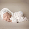 Newborn in white footed jumpsuit and hat