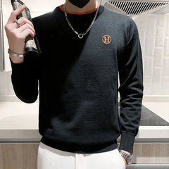 Black luxury men's golf sweater with orange accents and logo detail.