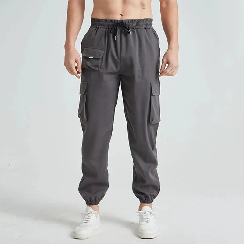 Close-up front view of gray men’s breathable cargo hiking pants with drawstring waist and spacious side pockets for gear storage.