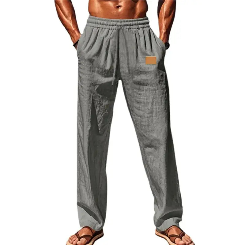 Gray men’s loose fit drawstring pants with elastic waistband, ideal for lounge, beach, or casual wear, styled with flip-flops.