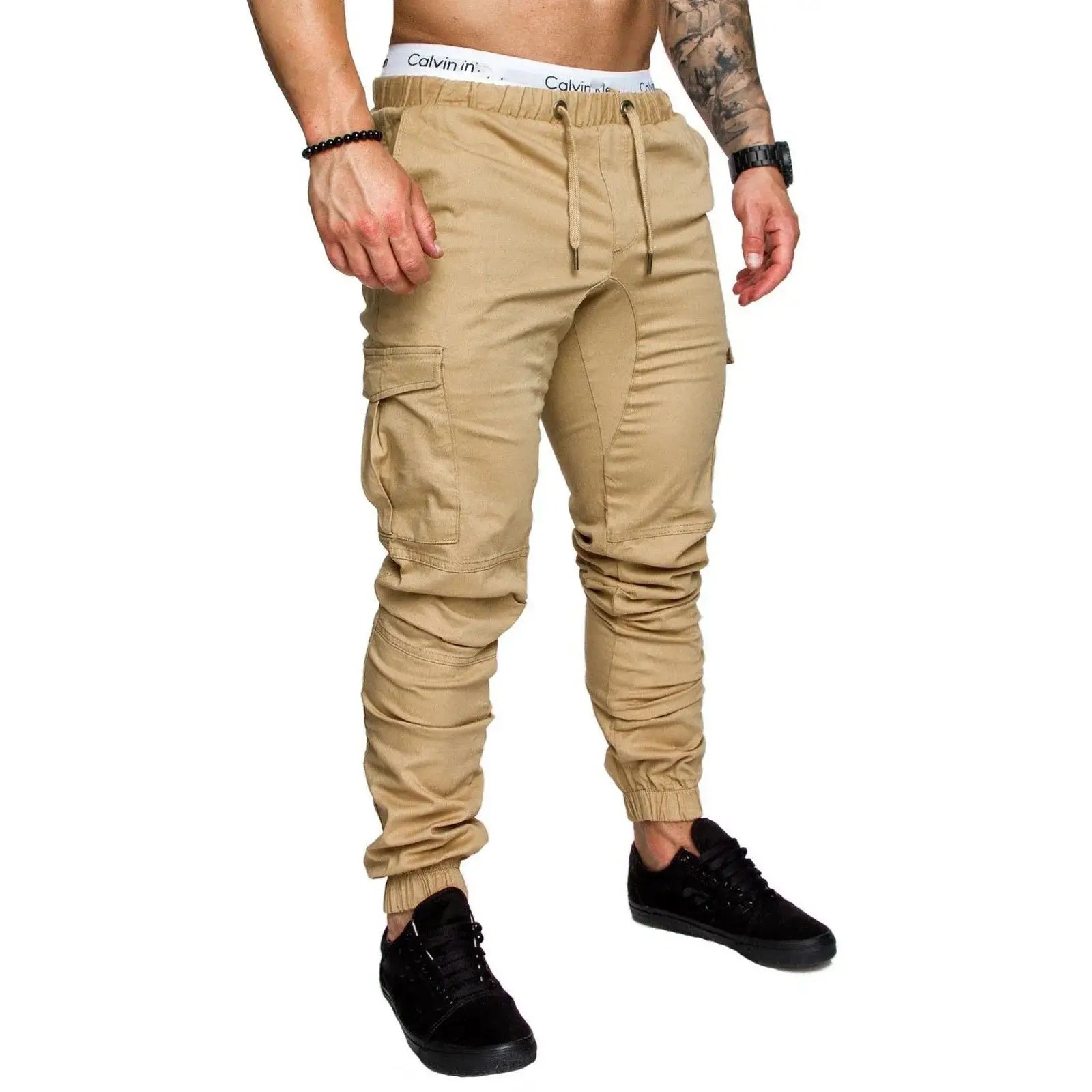 Beige men’s skinny cargo pants with drawstring waist and multiple pockets, styled for casual and athletic wear.