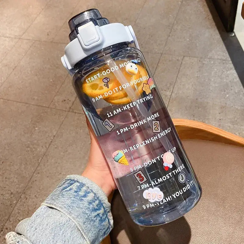Blue 2L leakproof sports water bottle with straw and time marker, filled with fruit slices and decorated with colorful motivational stickers.