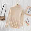 Beige women's turtleneck sweater on bed