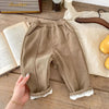 Brown warm winter pants for kids on a wooden table with books.