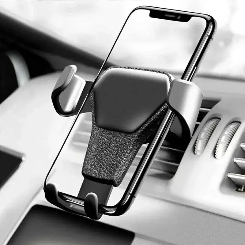 Black universal gravity phone holder securely gripping smartphone on car dashboard air vent with sleek leather texture.