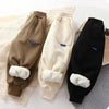 Three pairs of thick winter sports pants for kids in brown, cream, and black.