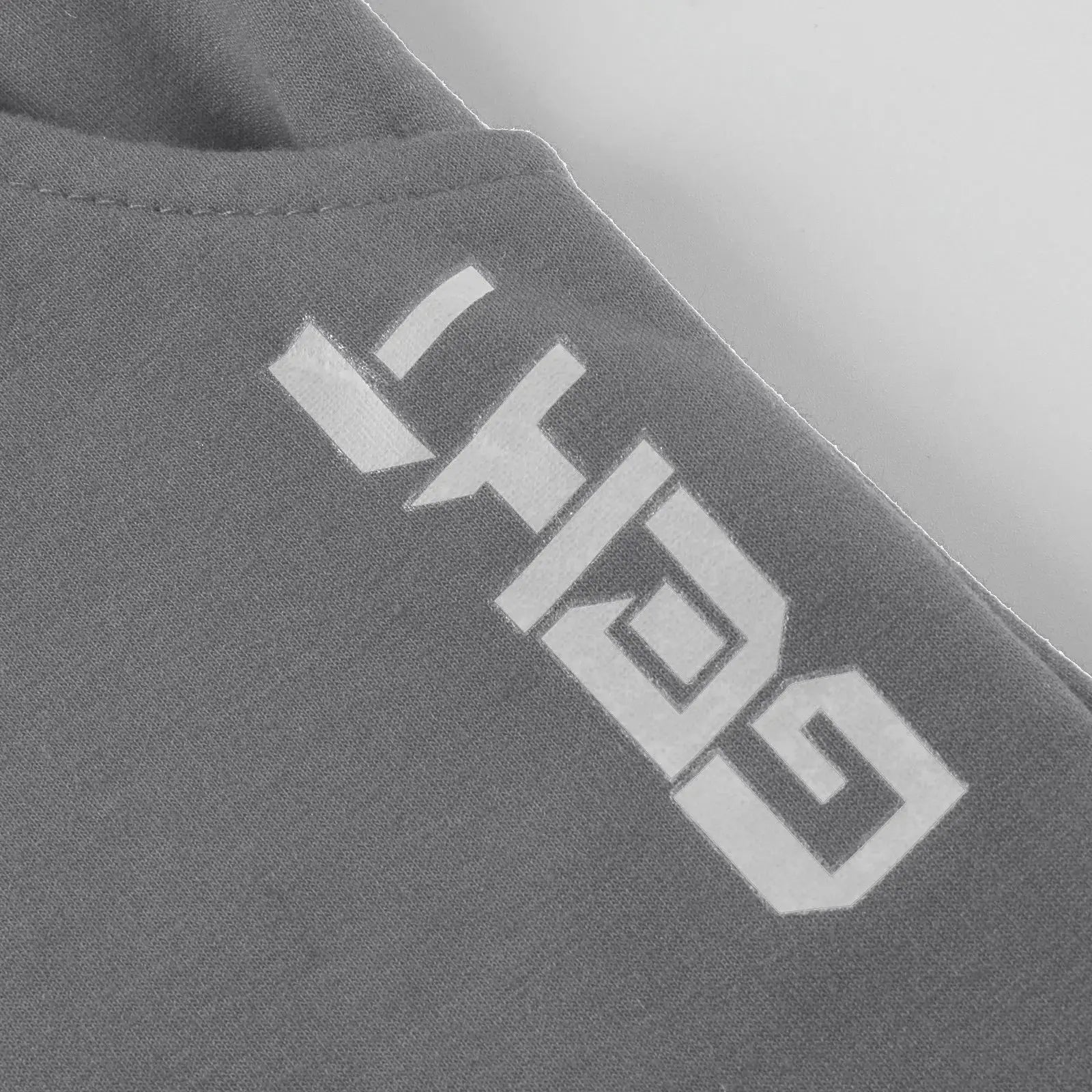 Close-up of logo detail on gray men’s athletic jogger sweatpants, showcasing branding and soft fabric texture for gym or training use.