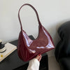 Glossy burgundy shoulder bag on black table