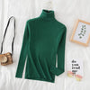 Green women's turtleneck sweater on bed