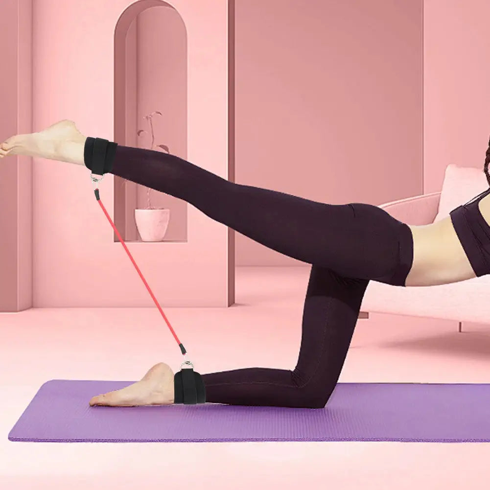 Woman using red leg resistance band with ankle straps during floor exercise to tone legs and glutes in a fitness studio setting.