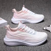 Pink and white casual running shoes on gray surface