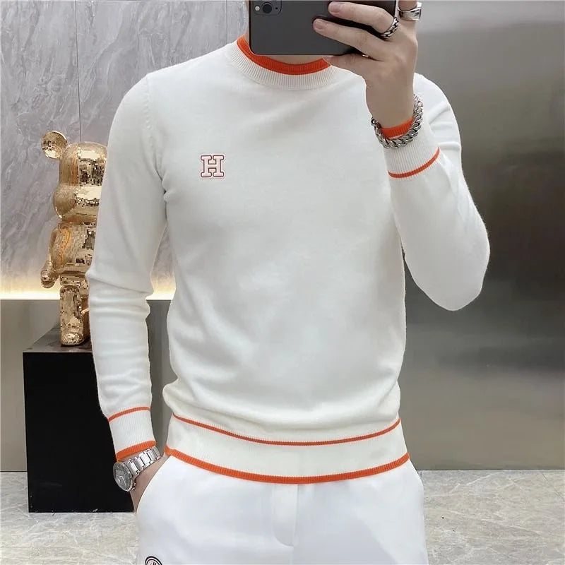 White luxury men's golf sweater with orange accents and logo detail.