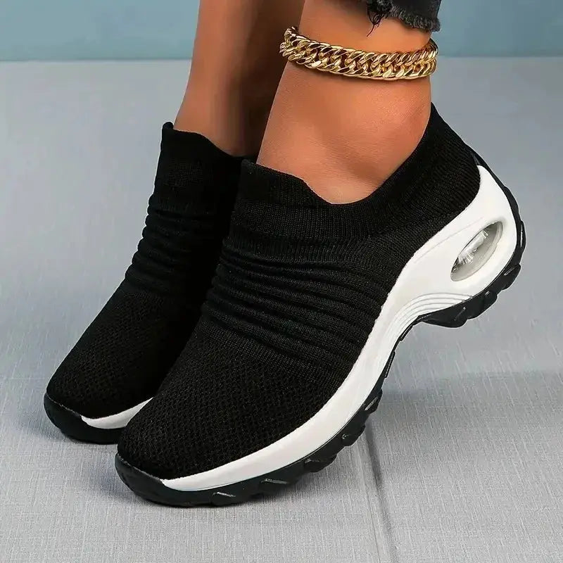 Women's slip-on sock sneakers in black with white air cushion sole, lightweight mesh design for walking, casual wear or training workouts.