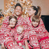 Family smiling in matching red Christmas pajamas by a tree