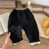 Black warm winter pants for kids displayed on a wooden table.