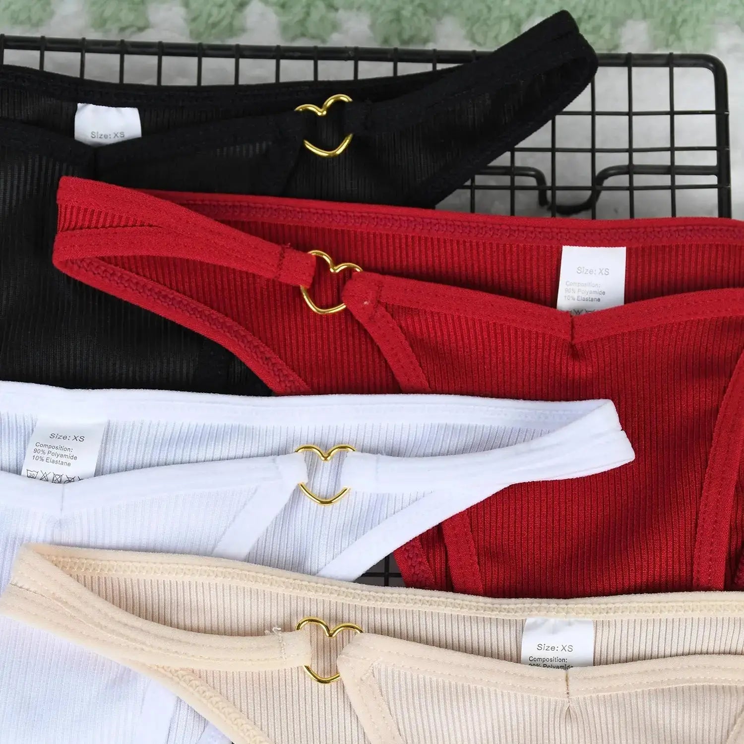 Close-up of ribbed cotton thongs in black, red, white, and beige featuring gold heart-shaped rings, part of 7-piece seamless underwear set.