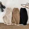 Kids' warm winter pants in beige, brown, and black on a bed.