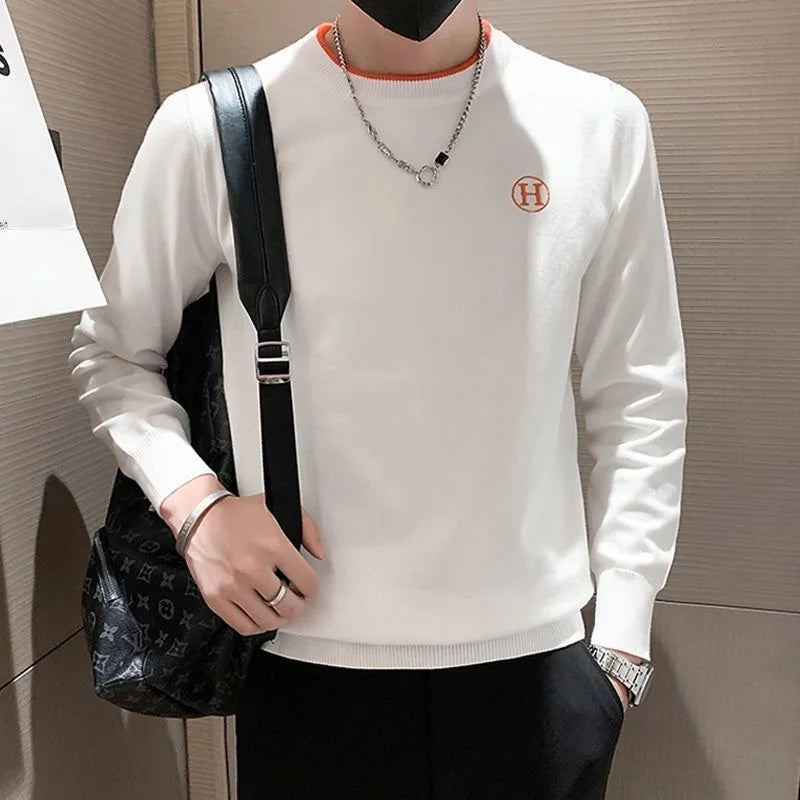 White men's golf sweater styled with a backpack and chain necklace.