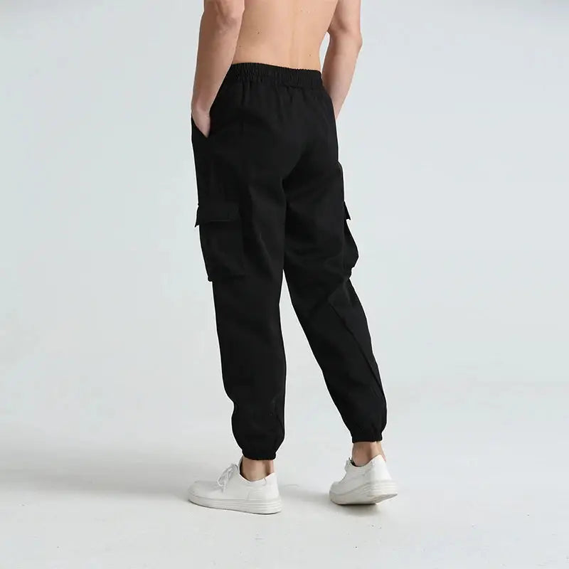 Side view of black men’s quick-dry cargo hiking pants with large utility pockets and tapered ankle cuffs for a modern fit.