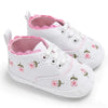 White baby shoes with pink floral embroidery