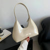 Shiny cream shoulder bag on black table