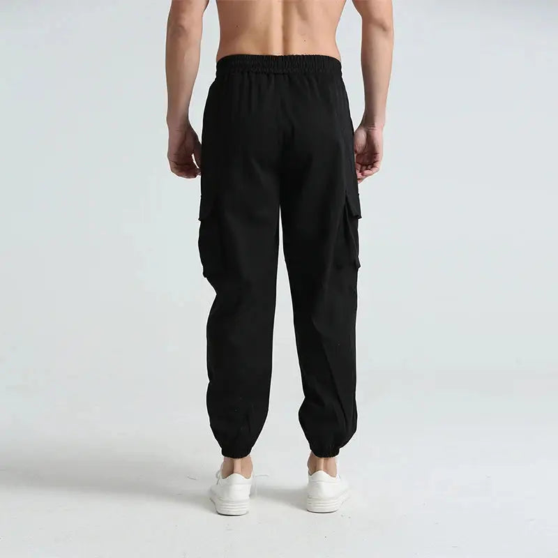 Rear view of black men’s breathable cargo hiking pants with elastic waistband and cuffed ankles, ideal for trekking and travel.
