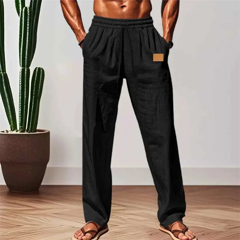 Men’s black breathable drawstring pants with elastic waist, styled indoors for lounge or casual wear with a relaxed fit.
