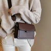 Brown faux leather crossbody bag worn by woman