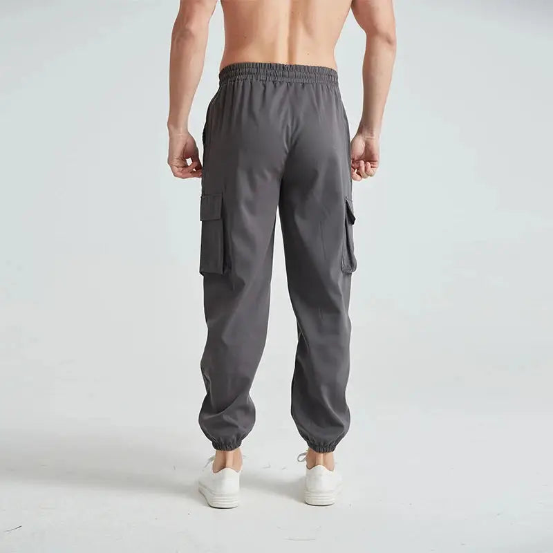 Back view of gray men’s lightweight cargo hiking pants featuring breathable material and elastic waistband for comfort and mobility.