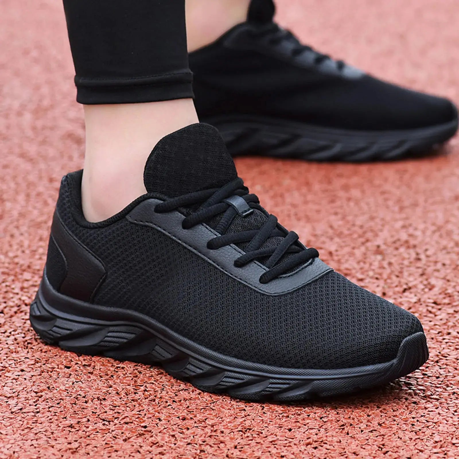 All-black men's leather sneakers with mesh upper and cushioned sole, designed for lightweight summer sports comfort.