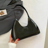 Glossy black shoulder bag on white surface