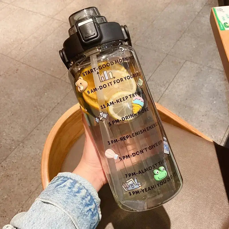 Black 2L leakproof water bottle with straw and time marker, decorated with fun stickers and citrus slices for fitness and hydration goals.