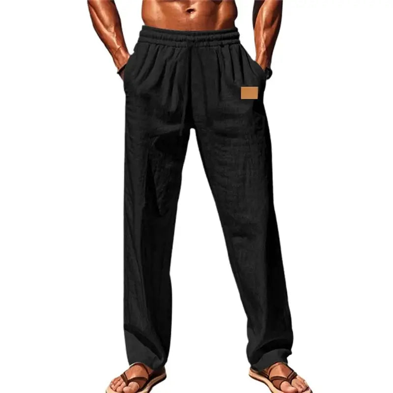 Black men’s breathable drawstring pants with elastic waistband and loose fit, styled for casual or beachwear with hands in pockets.